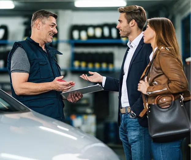Conseiller automobile discutant avec clients devant véhicule en garage